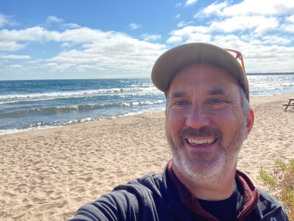 Portrait of Patrick Doran on a sunny beach.